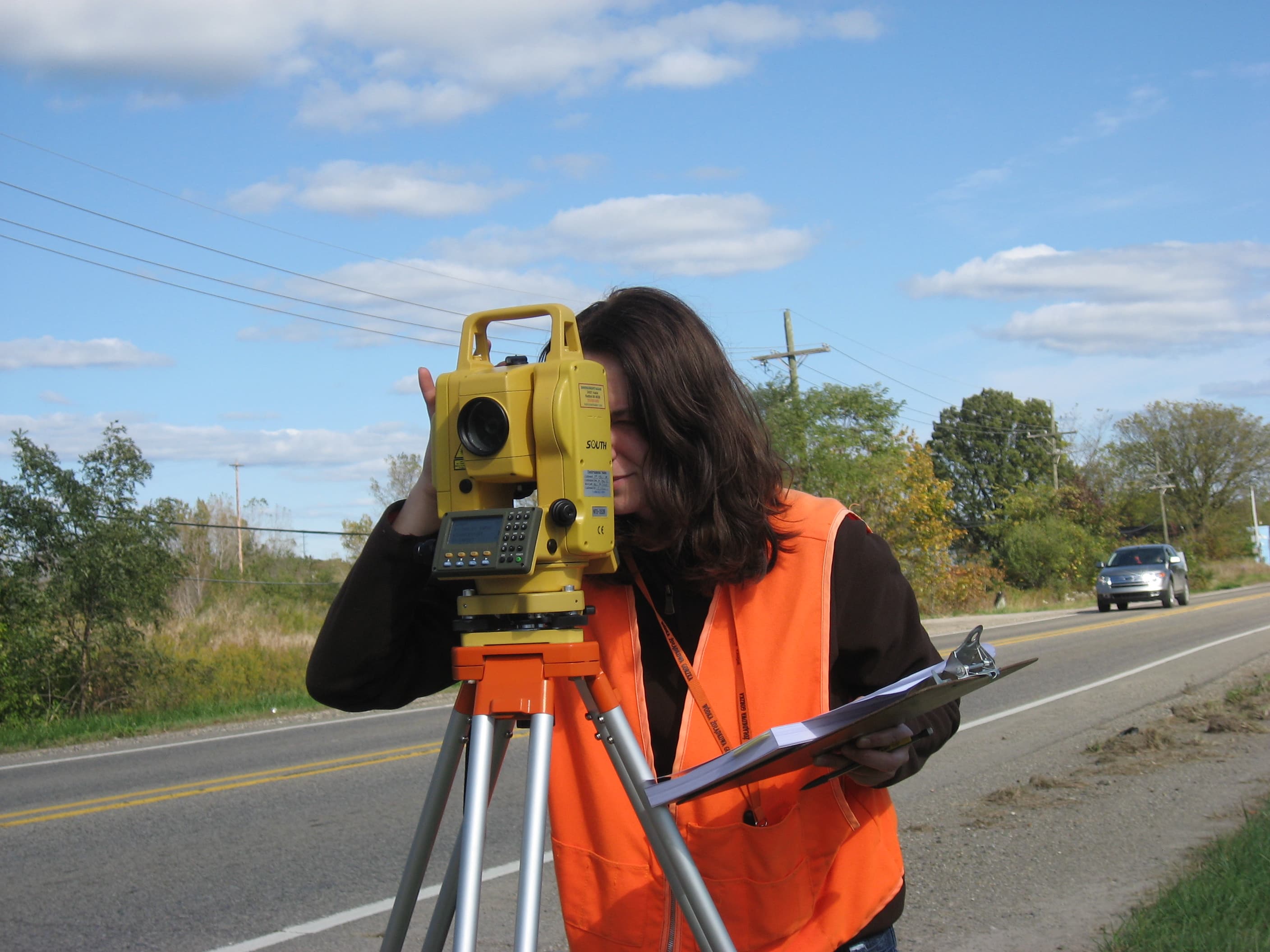 Surveyor looking through total station on roadside
